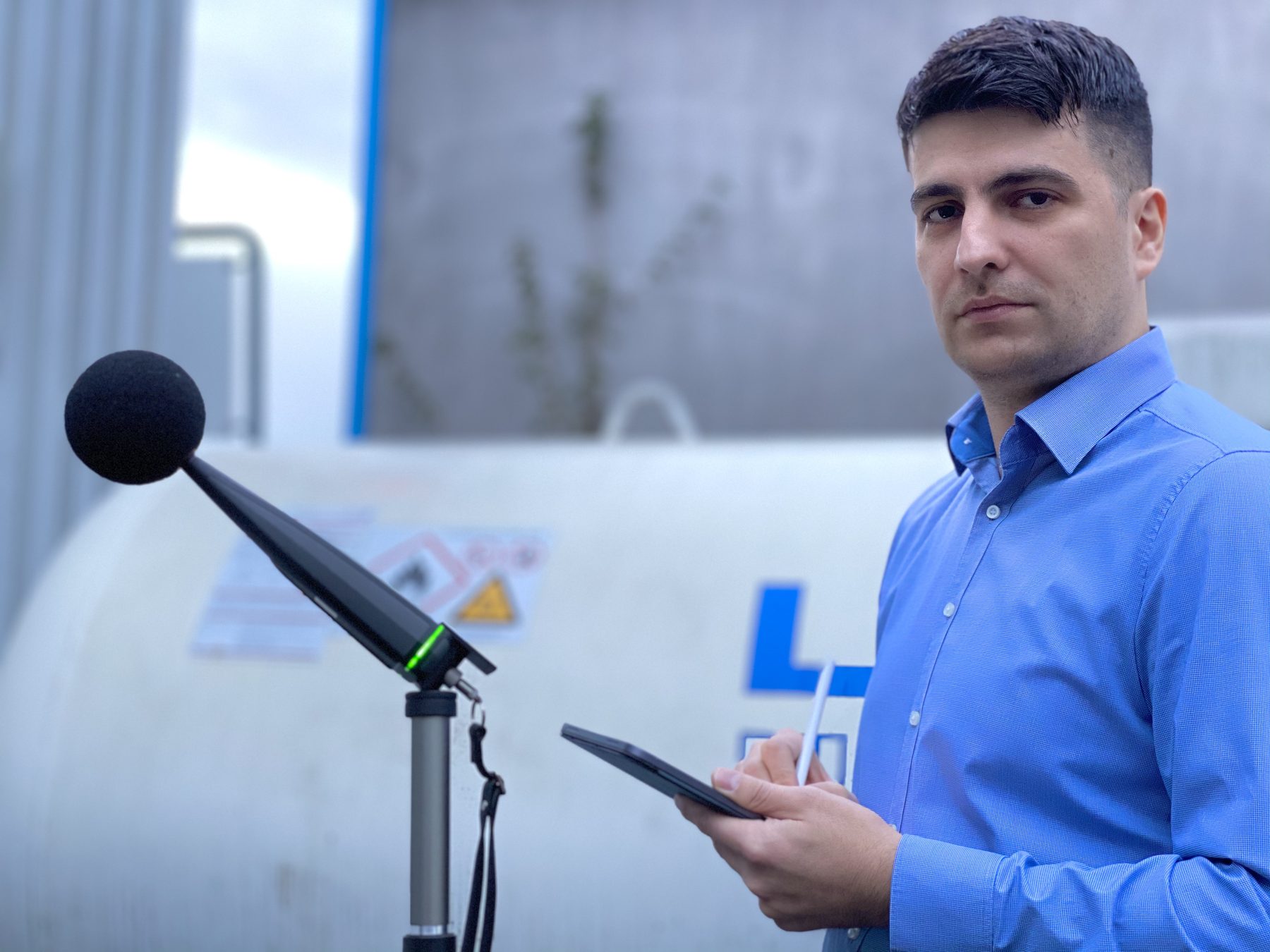 Orhan Cicekli, Fachkraft für Arbeitssicherheit, mit Schallpegelmesser vor einem Flüssiggastank